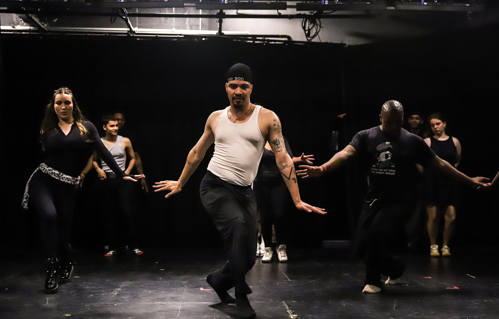 Dancers mid-step in a black-box studio during a ballroom class